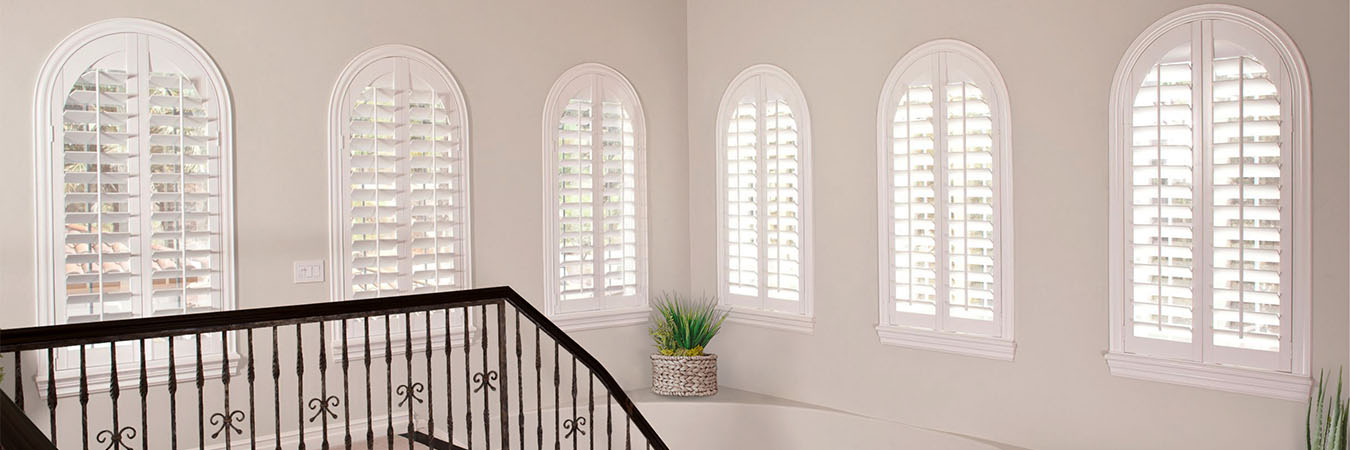  Six arched windows with white Polywood shutters in an elegant stairwell