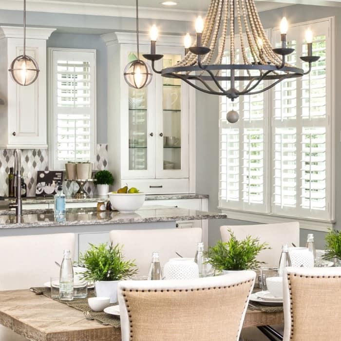 White Polywood shutters on large windows in a farmhouse-style living and dining room.