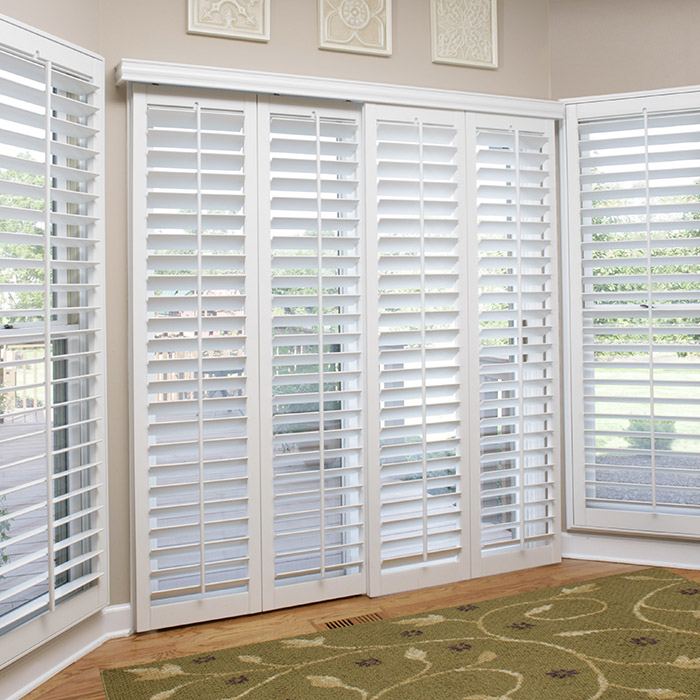 White shutters on a sliding glass door opens to a deck by the ocean.