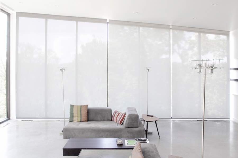 Motorized window shades make controlling natural light effortless in your San Diego great room. White motorized shades on a wall of tall great room windows