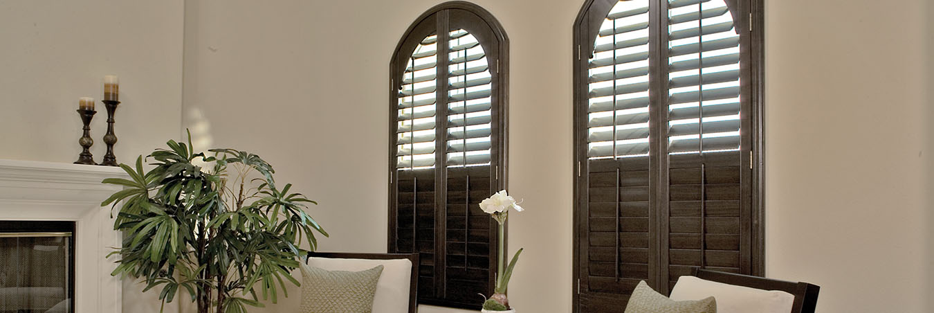 Wooden Ovation shutters with dark wood within a living room corner.