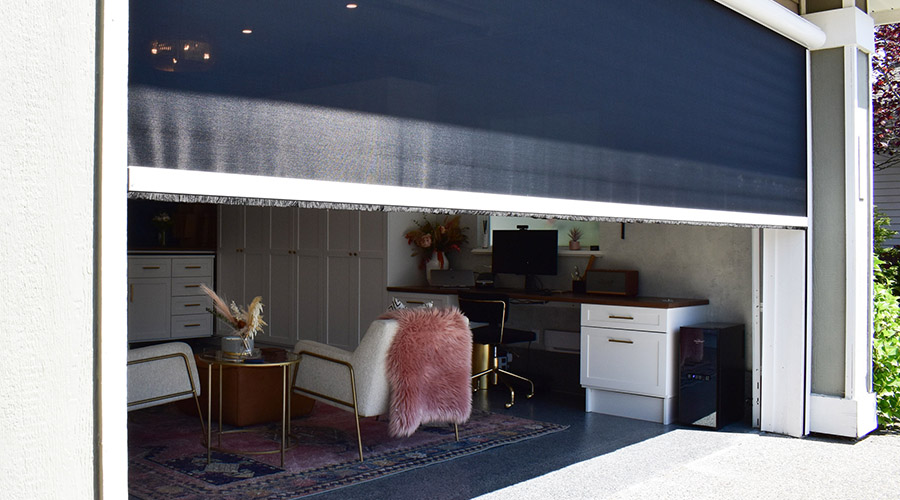 A large retractable screen door pulled half-way down over a garage door opening.