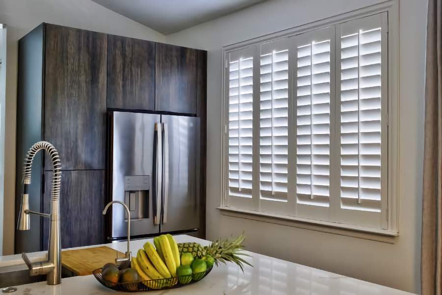 Homeowners use indoor window shutters in San Diego when they want attractive and functional window treatments. Polywood shutters on a large kitchen window