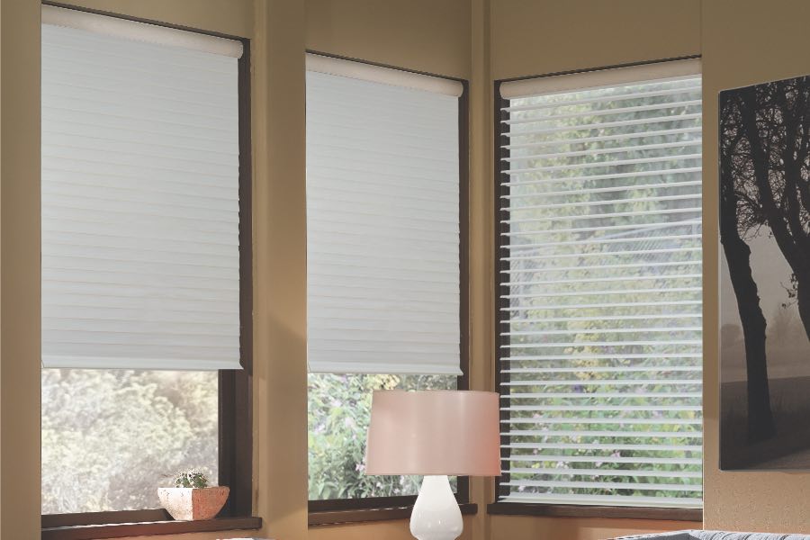 Opaque motorized window shades in San Diego keep hot UV rays out of your home. Gray motorized sheer shades on corner windows next to gray furniture