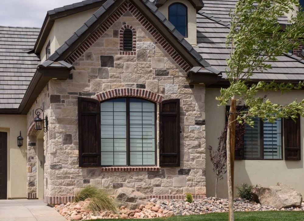 White interior shutters showing through two windows on the front of an attractive house