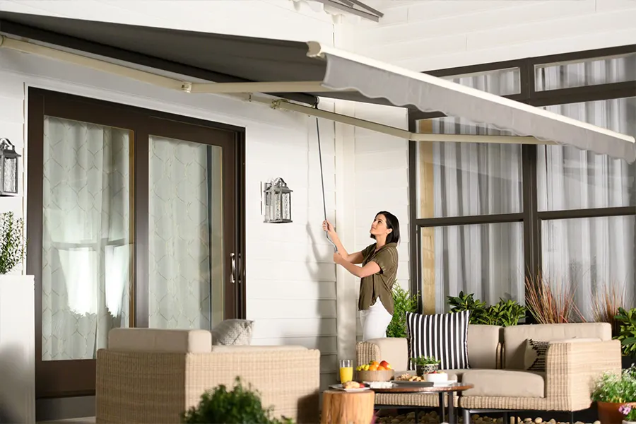 Both motorized and manual awnings are designed for easy use. A woman operating a manual awning